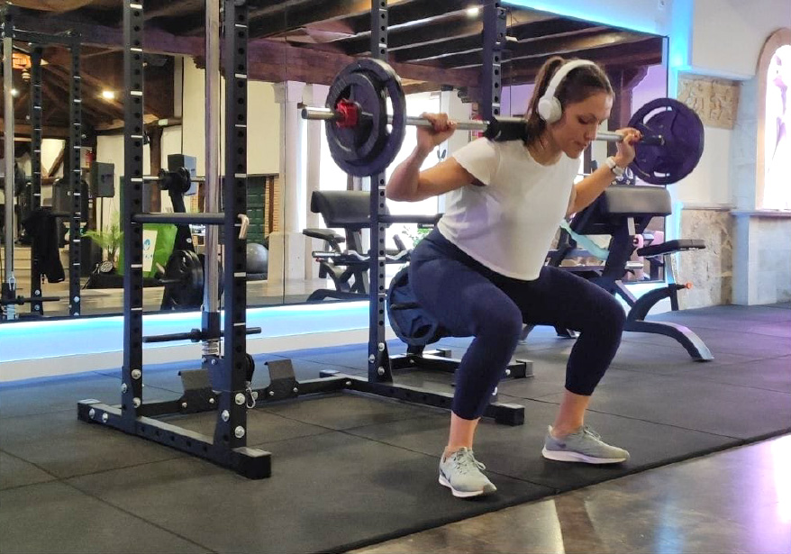 Chica haciendo sentadillas con pesa